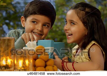Stock Photo - Boy and girl opening gifts on Diwali . Fotosearch