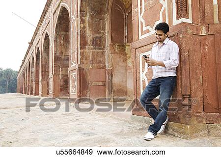 Stock Photo - Boy looking at an sms at Humayuns Tomb . Fotosearch