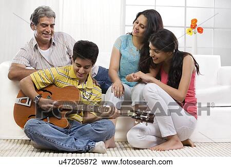 Boy playing the guitar for his family View Large Photo Image Stock Image - Boy playing the guitar for his family . Fotosearch