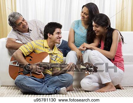 Boy playing the guitar for his family View Large Photo Image Stock Image - Boy playing the guitar for his family . Fotosearch