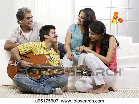 Boy playing the guitar for his family View Large Photo Image Stock Photo - Boy playing the guitar for his family . Fotosearch