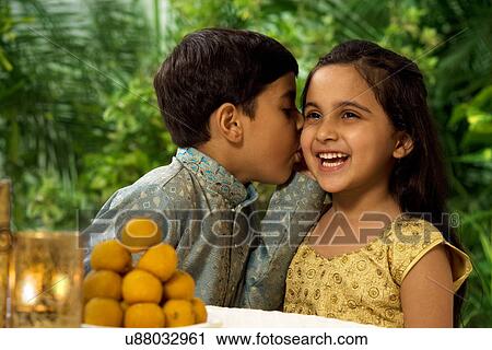Stock Image - Boy whispering in his sisters ear . Fotosearch