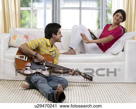 Stock Image - Brother disturbing his sister . Fotosearch