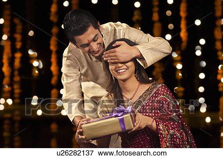 Stock Photo - Brother surprising his sister with a gift. Fotosearch