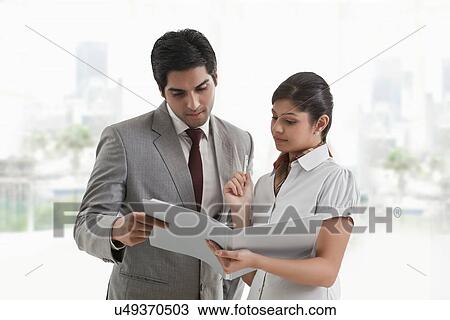 Stock Image - Business colleagues in discussion about document in office . Fotosearch