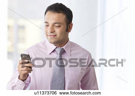 Stock Photograph - Business executive reading an sms on a mobile phone . Fotosearch