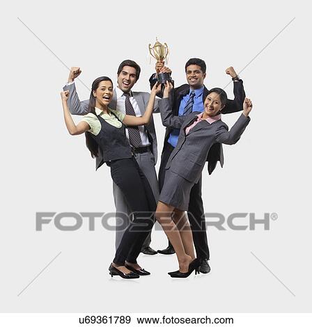 Stock Photo - Business executives rejoicing while holding trophy . Fotosearch