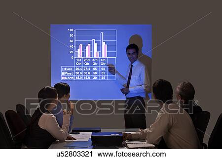 Stock Image - Businessman giving graph presentation to executives in meeting . Fotosearch