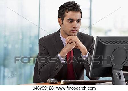 Businessman looking at monitor screen in office View Large Photo Image Stock Photo - Businessman looking at monitor screen in office . Fotosearch