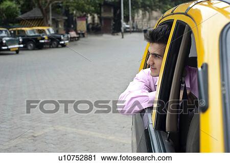 Stock Image - Businessman looking out of a taxi . Fotosearch