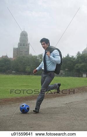 Stock Image - Businessman playing with a football . Fotosearch
