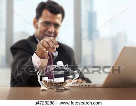 Businessman putting coin into piggy bank View Large Photo Image Stock Image - Businessman putting coin into piggy bank . Fotosearch