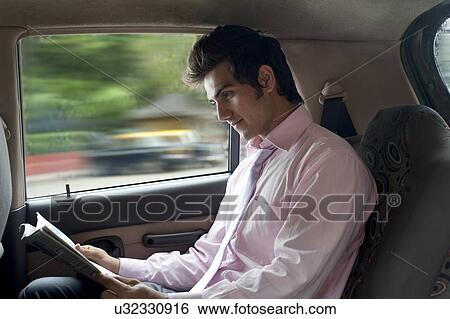 Businessman reading a newspaper in a car View Large Photo Image Stock Photograph - Businessman reading a newspaper in a car . Fotosearch
