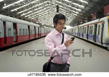 Businessman reading an sms at a train station View Large Photo Image Stock Photograph - Businessman reading an sms at a train station . Fotosearch