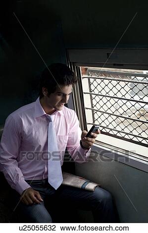 Stock Image - Businessman reading an sms in a train . Fotosearch