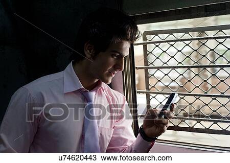Stock Image - Businessman reading an sms in a train . Fotosearch
