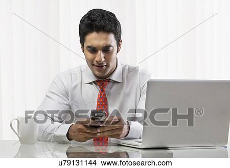 Businessman sending a text message View Large Photo Image Picture - Businessman sending a text message . Fotosearch