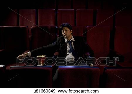Stock Photo - Businessman sleeping inside a cinema hall . Fotosearch