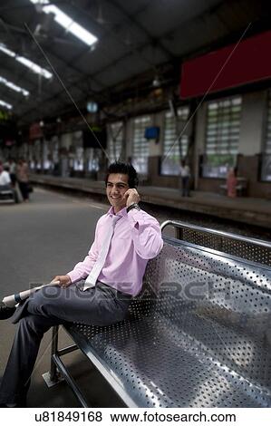 Stock Photo - Businessman talking on a mobile phone at a train station . Fotosearch