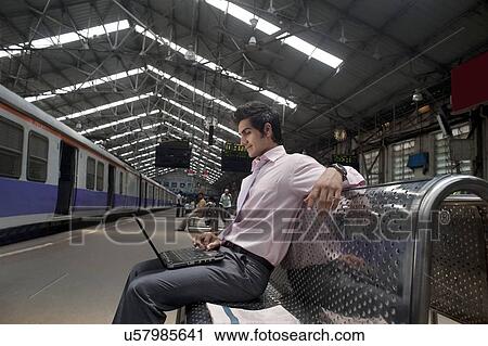 Stock Image - Businessman with a laptop at a train station . Fotosearch