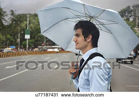 Businessman with an umbrella crossing a road View Large Photo Image Stock Image - Businessman with an umbrella crossing a road . Fotosearch
