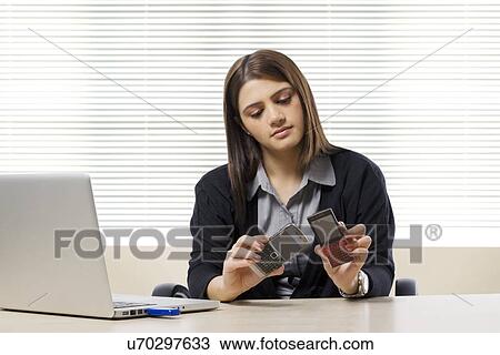 Stock Image - Businesswoman comparing two mobile phones . Fotosearch