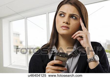 Stock Photography - Businesswoman contemplating while holding a mobile phone . Fotosearch