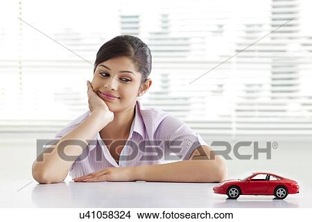 Businesswoman dreaming at office white looking at car model View Large Photo Image Picture - Businesswoman dreaming at office white looking at car model . Fotosearch