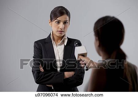 Picture - Businesswoman giving an interview to a reporter against colored background . Fotosearch