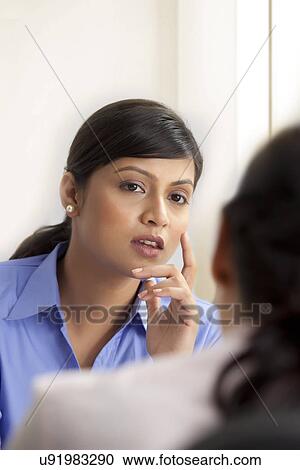 Stock Image - Businesswoman listening to other female executive . Fotosearch
