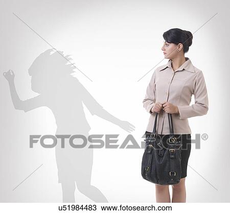 Stock Image - Businesswoman looking at shadow dancing against gray background. Fotosearch