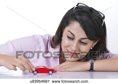 Businesswoman looking at toy car against white background View Large Photo Image Stock Photo - Businesswoman looking at toy car against white background. Fotosearch