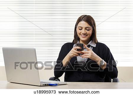 Stock Image - Businesswoman reading a message on a mobile phone . Fotosearch