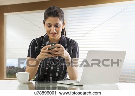 Stock Image - Businesswoman sending an sms . Fotosearch