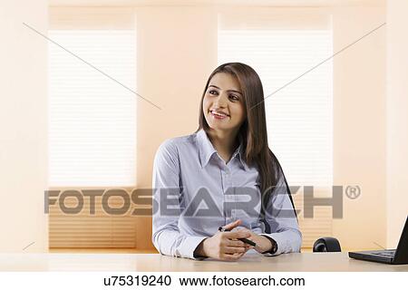 Stock Image - Businesswoman sitting in an office . Fotosearch