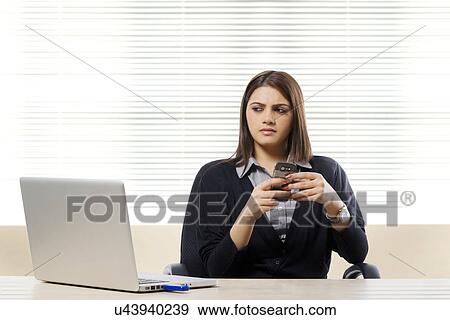 Stock Photo - Businesswoman thinking while holding a mobile phone . Fotosearch
