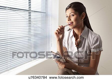 Picture - Businesswoman thinking while solving puzzle on newspaper . Fotosearch