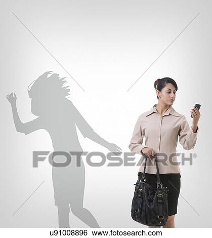 Stock Photograph - Businesswoman using mobile phone against shadow dancing over gray background. Fotosearch