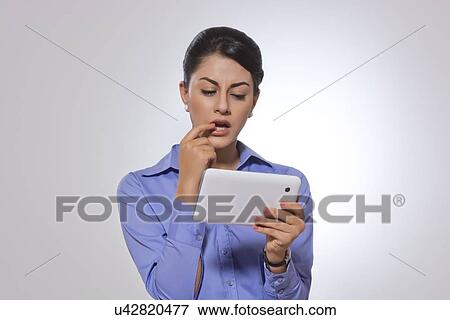 Businesswoman working on digital tablet over gray background View Large Photo Image Stock Photo - Businesswoman working on digital tablet over gray background. Fotosearch
