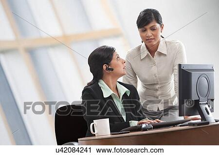 Stock Image - Businesswomen conversing about new plan . Fotosearch