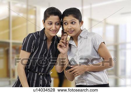 Stock Photo - Businesswomen listening to a message on a mobile phone . Fotosearch