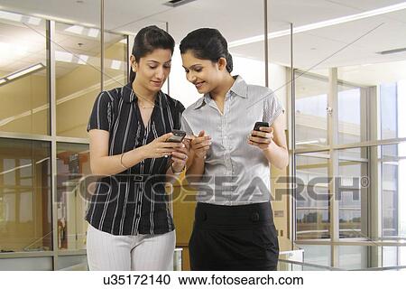 Stock Image - Businesswomen reading a message on a mobile phone . Fotosearch