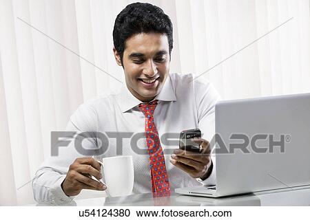 Stock Image - Businesswomen reading a message on a mobile phone . Fotosearch