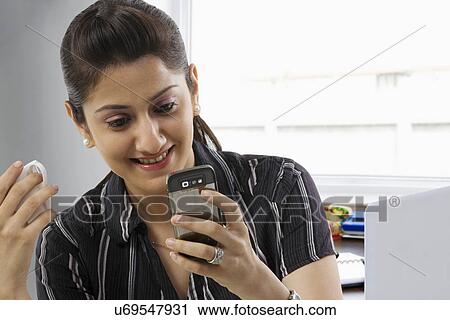 Stock Image - Businesswomen reading a message on a mobile phone . Fotosearch