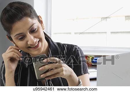 Stock Image - Businesswomen reading a message on a mobile phone . Fotosearch