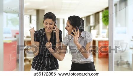 Businesswomen with mobile phones rejoicing View Large Photo Image Stock Photography - Businesswomen with mobile phones rejoicing . Fotosearch