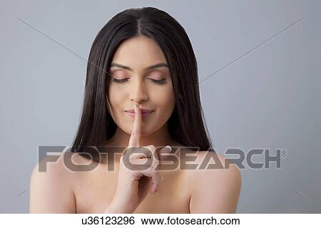 Stock Photograph - Calm woman with eyes closed gestures for silence over colored background . Fotosearch
