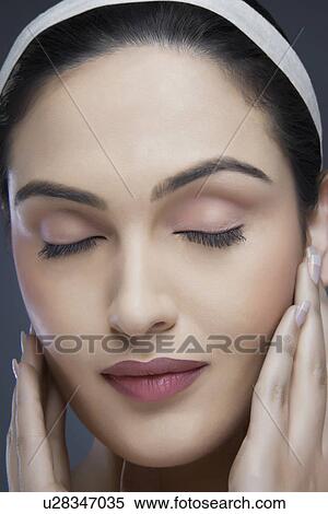 Calm young woman touching her face over colored background View Large Photo Image Stock Photography - Calm young woman touching her face over colored background . Fotosearch