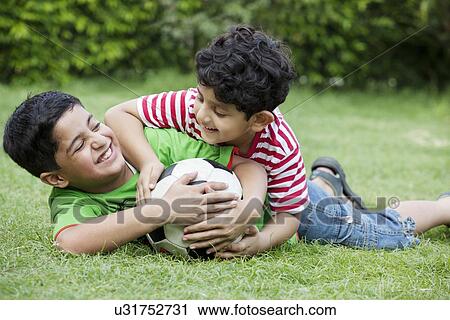 Cheerful brothers playing with soccer ball in park View Large Photo Image Stock Image - Cheerful brothers playing with soccer ball in park . Fotosearch