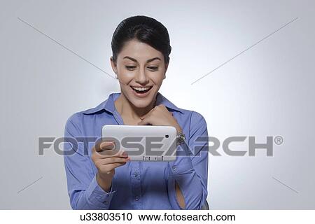 Cheerful businesswoman using tablet computer against gray background View Large Photo Image Stock Image - Cheerful businesswoman using tablet computer against gray background. Fotosearch